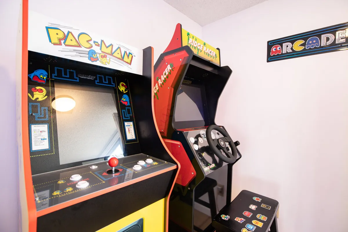 This image focuses on classic arcade machines—Pac-Man and Ridge Racer—set against a backdrop ideal for friendly competitions and late-night entertainment. The inviting setup encourages playful social interaction and memorable group experiences.