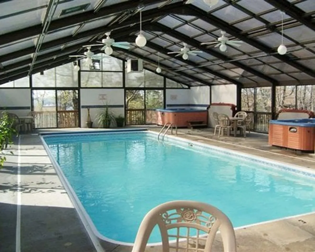A tranquil indoor swimming pool area with hot tubs, ceiling fans, and natural light filtering in. The setting is spa-like, inviting guests to relax, swim, or socialize, reinforcing the wellness and relaxation theme of the section.