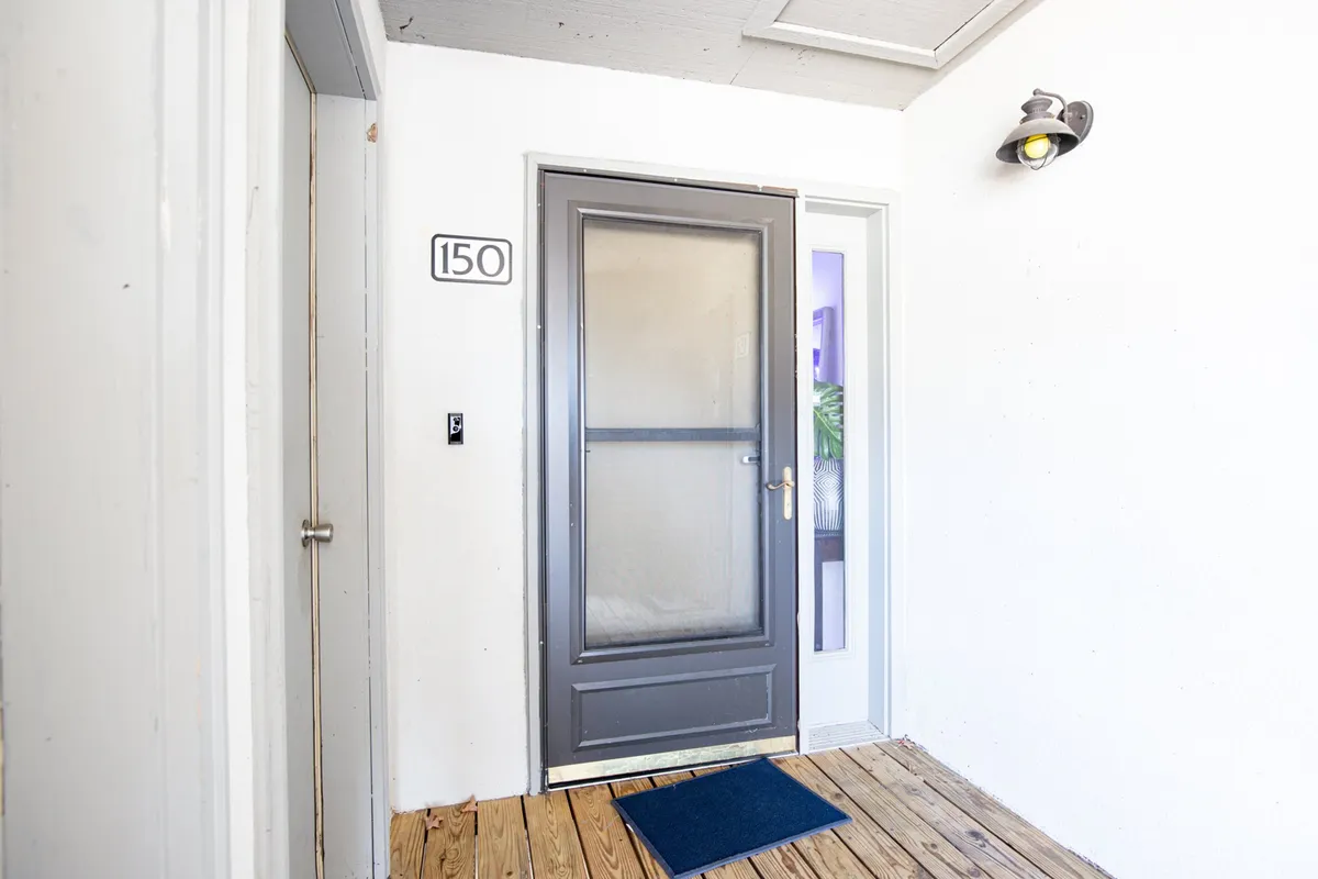 This image presents the home's entryway, featuring a screen door with a visible doorway number, and warm wooden flooring that creates an inviting first impression. The fresh air and cozy entrance atmosphere are prominent, setting the tone for the rest of the home.